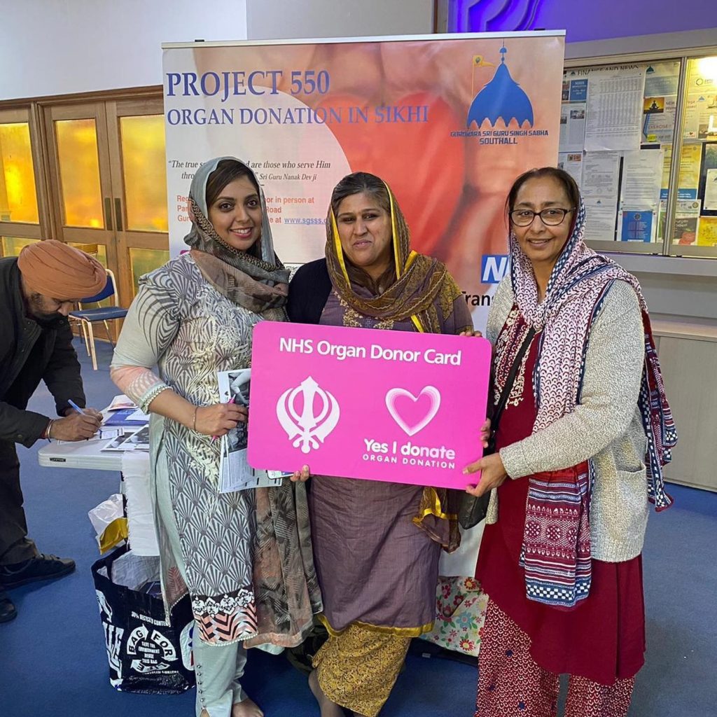 Three ladies holding a placard that says yes I donated for organ donation
